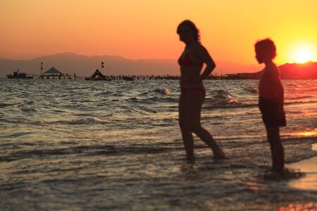 woman and boy on the beach at eveningの写真素材