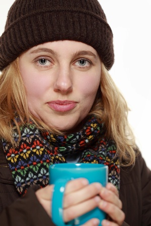 woman looking cold in winter clothes drinking a hot drinkの写真素材