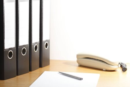 office desk with folders and phone on a white backgroundの写真素材