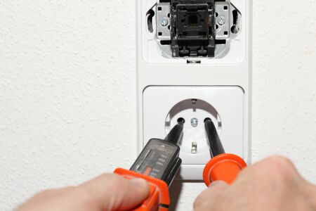 Electrician installing white wall socket and test itの写真素材