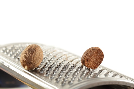 two nutmegs and grater with white backgroundの写真素材
