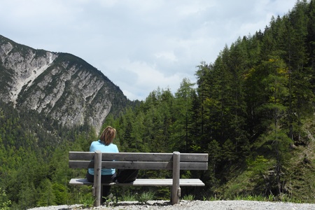 woman is taking a rest on a bench in the mountainsの写真素材