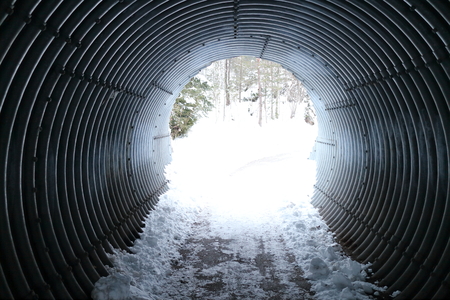 a dark round passage with light on the end