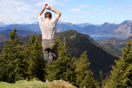 man is jumping on top of a mountainの写真素材