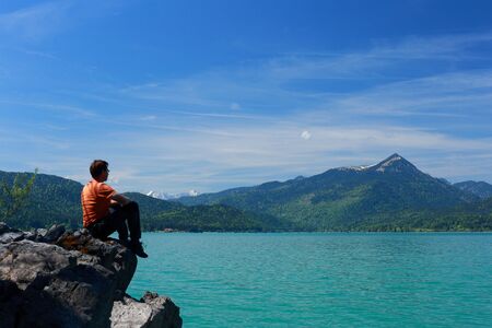 man is sitting on top of a rockの写真素材