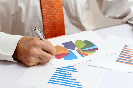 businessman is writing on different documents with graphの写真素材