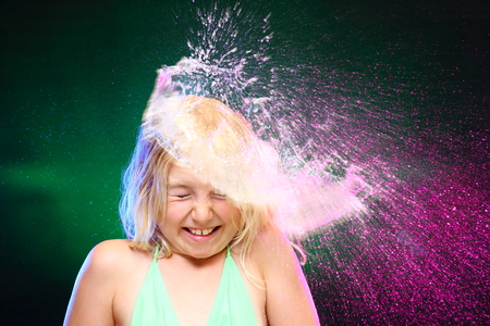 surprised young girl with coloful water showerの写真素材