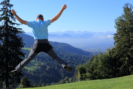 jumping up man with mountains in backgroundの写真素材