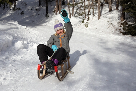girl on sledge with hand up in winterの写真素材