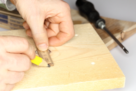 a worker is marking a wooden plate on work bench