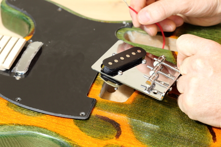 technician is fixing a pick-up on a guitarの写真素材