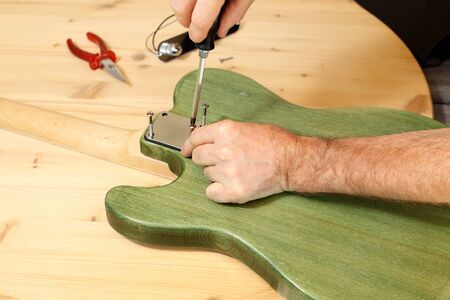 man is building an electrical guitar on a work benchの写真素材