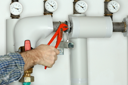 plumber is fixing a valve in heating room