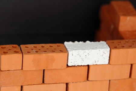 a red wall with one white brick as connectionの写真素材