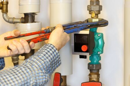 worker is changing an electric pump in a heating room