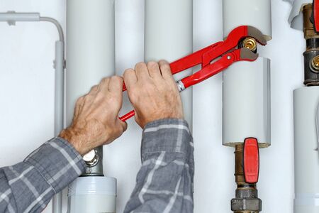 worker with gripper in hand is fixing a pipeの写真素材