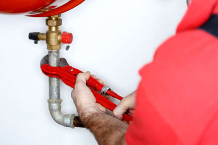 plumber is repairing a pipe with red toolの写真素材