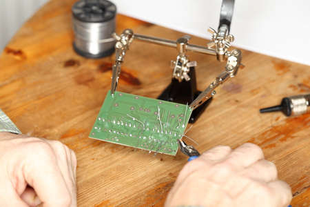 worker is fixing a green electronic board with toolsの写真素材