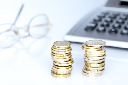coin stacks with calculator and pen on a white deskの写真素材