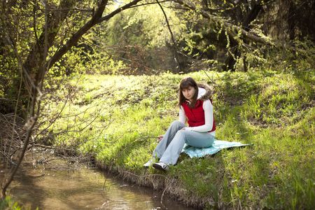 Girl sitting and resting near a riverの写真素材