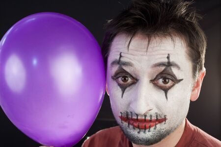 Clown with a balloon looking at camera on a black backgroundの写真素材