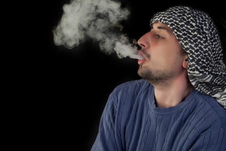 Young man enjoying hookah on a black background