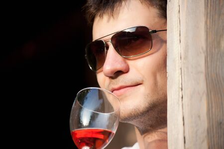 Young man with glasses drinking wineの写真素材