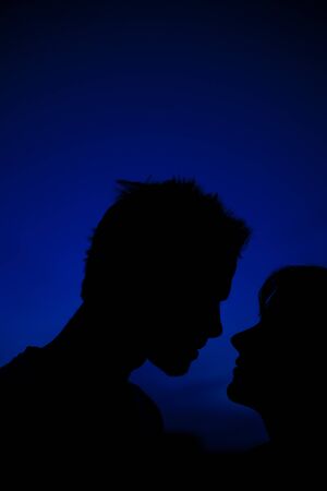 Silhouette of young man and woman in the nightの写真素材