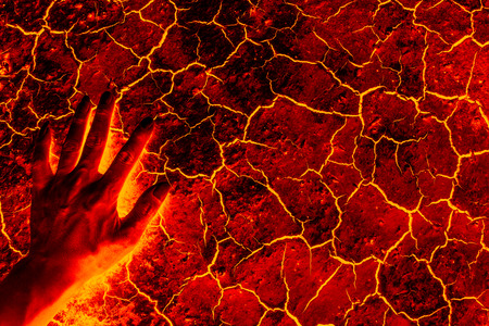 Global warming, ground volcanic eruption, Hand standing on the ground lava.の写真素材