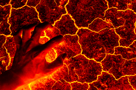 Global warming, ground volcanic eruption, Hand standing on the ground lava.の写真素材