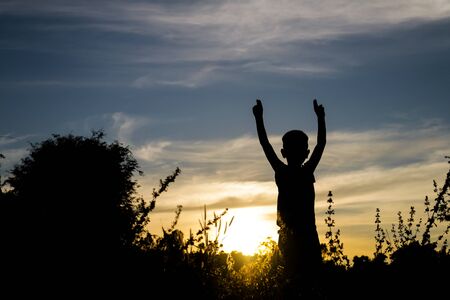 Children standing lift hand bye sun silhouette.の写真素材
