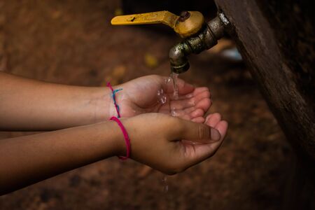Close up Asian boy open metal water faucet empty land.  Water is life concept.の写真素材