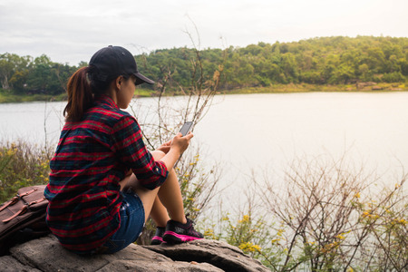 Woman with backpack sit by the the riverside.の写真素材