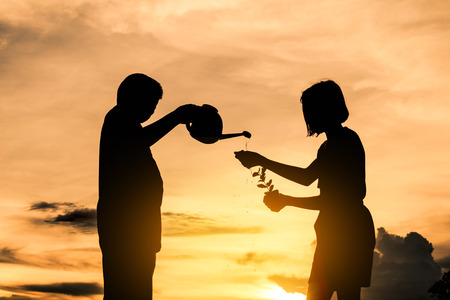 Silhouette boys and girls are helping to plant trees, Concept love the world.の写真素材