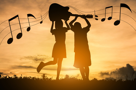 Silhouette boy and girls are enjoying playing music.の写真素材