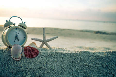 Clock and starfish on the sea white sand.の写真素材