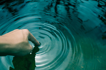 The hands dipped in blue water until the waves.