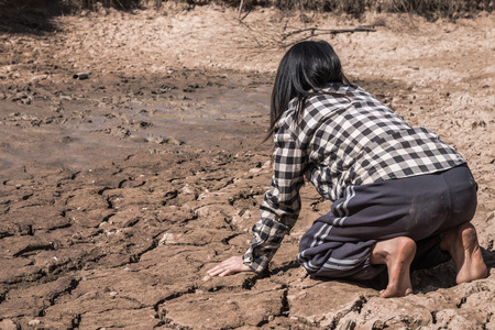 The woman sat on a barren ground with despair.の写真素材