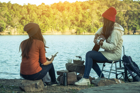 Tourists women and friends camping on the river on holiday.