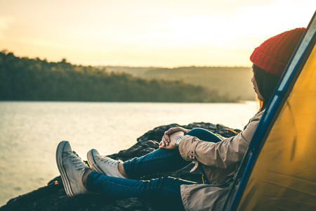 Woman tourist sitting on the river surrounded by rivers and mountains.の写真素材