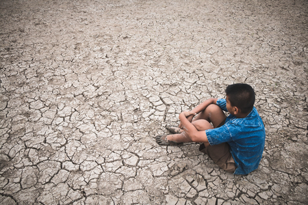 Men on ground cracked dry due to drought, food shortages and water,  Concept drought and crisis environment.の写真素材