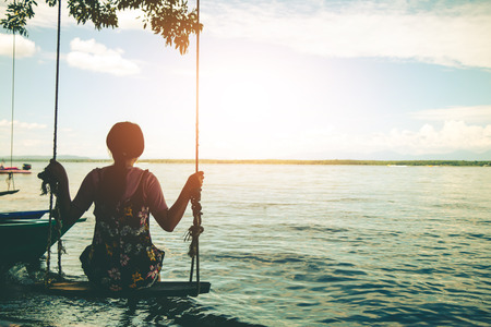 Woman sitting beach swings in beautiful nature.の写真素材