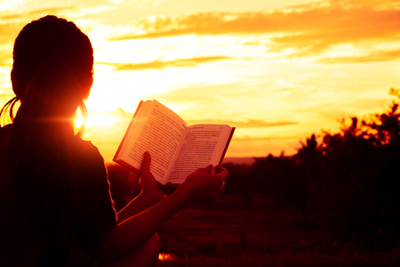 Silhouette women sitting read a book on holiday with beautiful nature.の写真素材