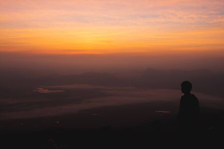The tourists stand in the mountains amid the misty atmosphere landscape.の写真素材