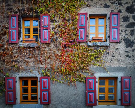 Aold house with colourful shutters and and autum leafs growin on the wallの写真素材