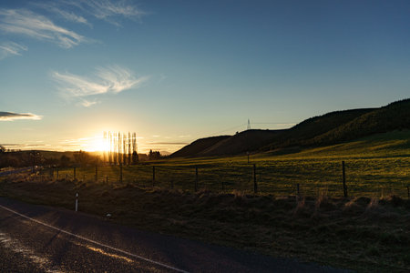 A stunning sunset casts beautiful colors over the rolling hills and winding road aheadの写真素材