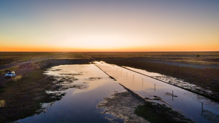 Experience the Serene Sunset Over Tranquil Waterways Amidst a Vast and Beautiful Landscapeの写真素材