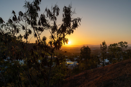 A beautiful sunset over a vibrant cityscape with trees in the foregroundの写真素材