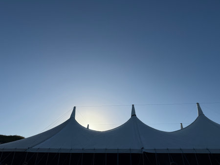 A white tent stands silhouetted against a blue skyの写真素材
