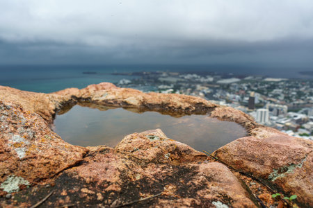 Closeup of a puddle in rocks with a stormy scenic backgroundの写真素材